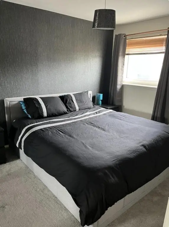 a bedroom with a large bed with black sheets and pillows at Townhead Road in Inverurie