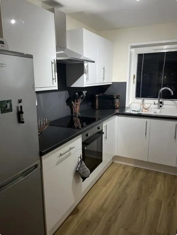 a kitchen with white cabinets and a black counter top at Townhead Road in Inverurie