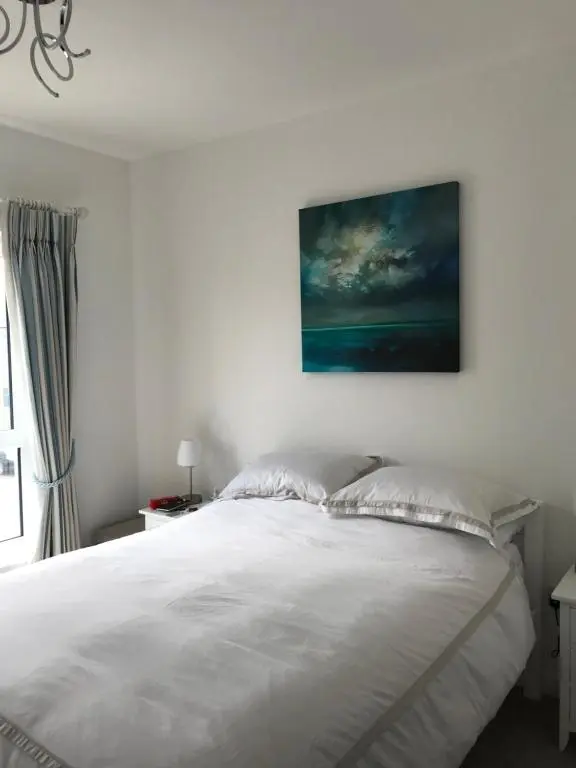 a bedroom with a white bed with a painting on the wall at Amazing views of Inverness in Inverness