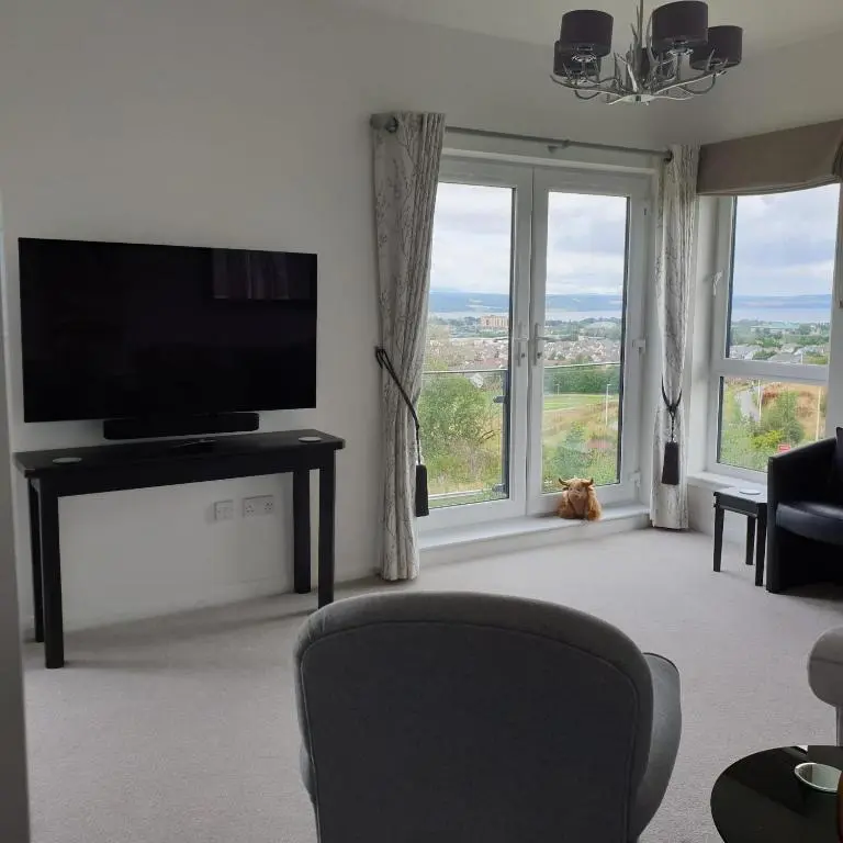 a living room with a television and a cat sitting in front of a window at Amazing views of Inverness in Inverness
