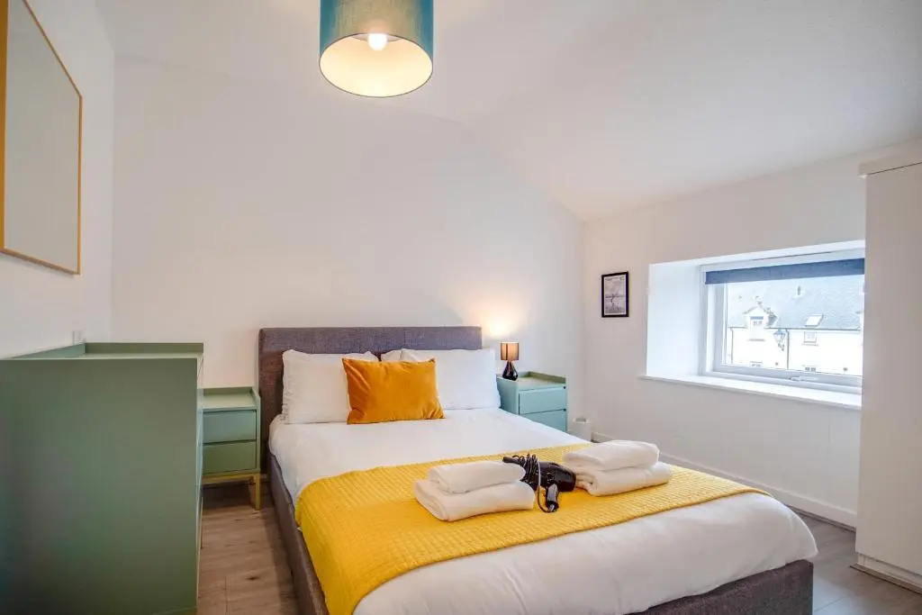 a bedroom with a large bed with towels on it at Comfortable 2-Bedroom Inverness Flat in Inverness