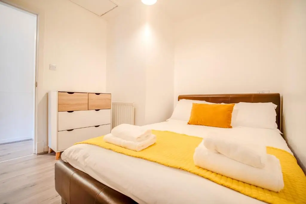 a bedroom with a bed with a yellow blanket and a dresser at Comfortable 2-Bedroom Inverness Flat in Inverness