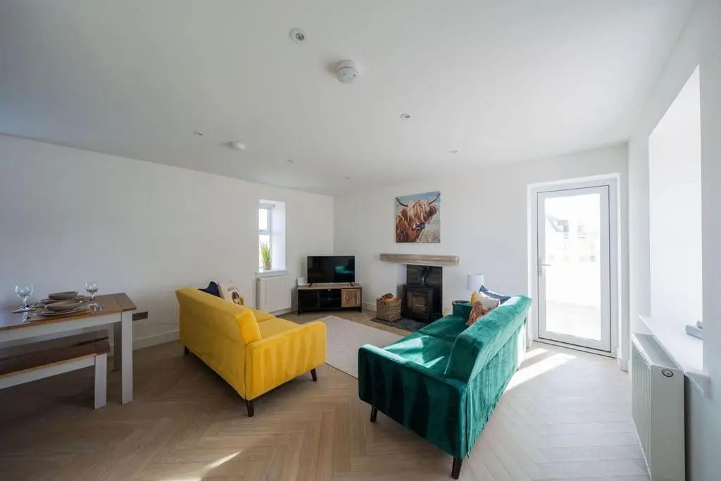 a living room with a green couch and yellow chairs at Easter Cottage -4 Bed Converted Barn Cottage in Turriff