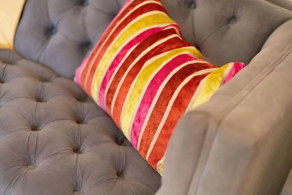 a striped pillow sitting on top of a couch at Red Squirrel Cottage, Family & Pet Friendly Adventure Retreat, Strathdon, Aberdeenshire in Towie