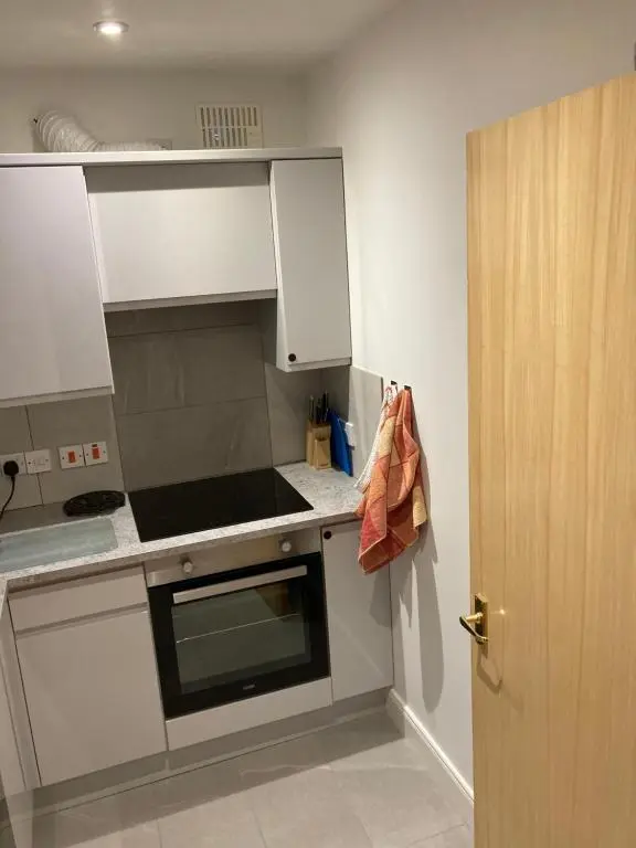 a kitchen with white cabinets and a stove top oven at Flat 2 at Inverness City in Inverness