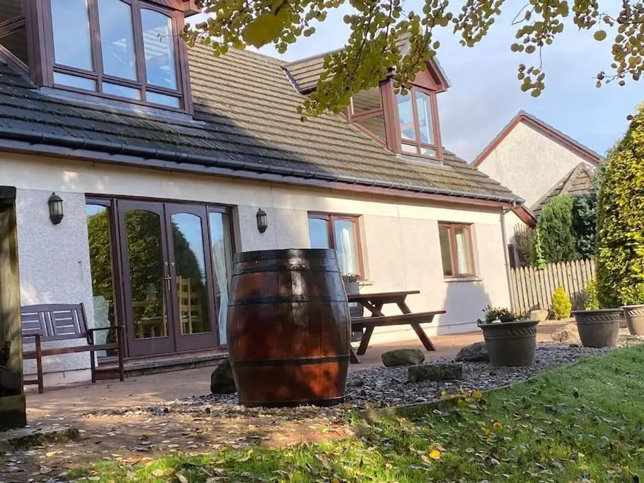 a large barrel sitting outside of a house at Dalfaber House Luxury holidays in the Highlands in Aviemore