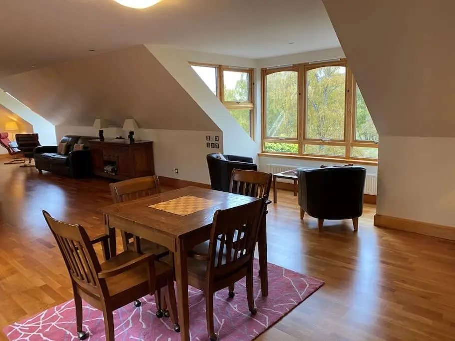 a dining room and living room with a table and chairs at Dalfaber House Luxury holidays in the Highlands in Aviemore