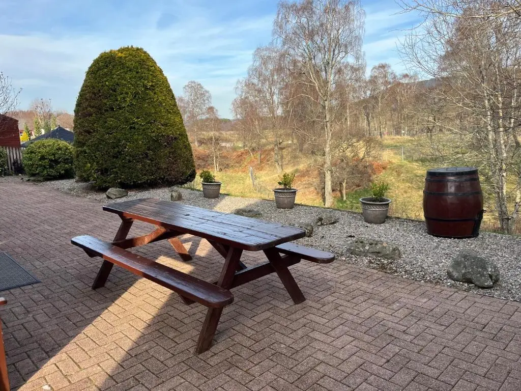 a picnic table and a barrel on a brick patio at Dalfaber House Luxury holidays in the Highlands in Aviemore