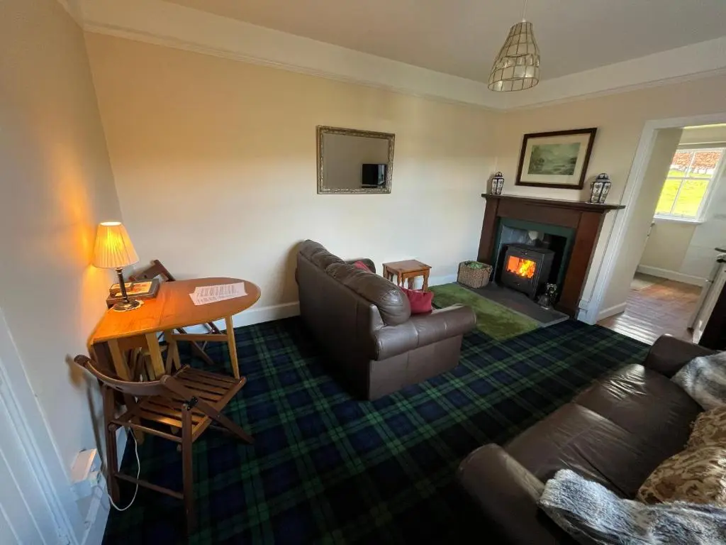 a living room with a couch and a table and a fireplace at Old Lock-keeper's Cottage in Fort Augustus