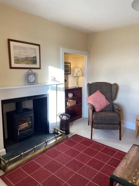 a living room with a fireplace and a chair at Dalvey Mill Cottage in Forres