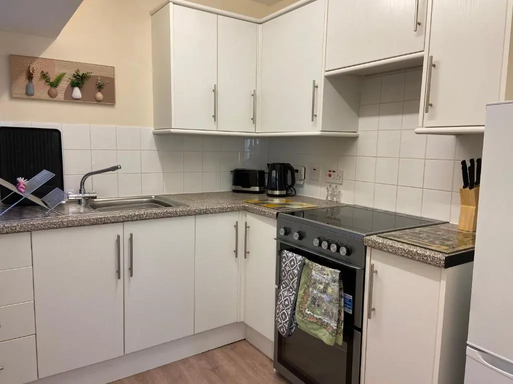a kitchen with white cabinets and a black stove top oven at Dalvey Mill Cottage in Forres