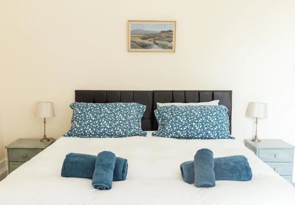 a bedroom with a white bed with blue pillows at Dalvey Abbotshill Farm House in Forres