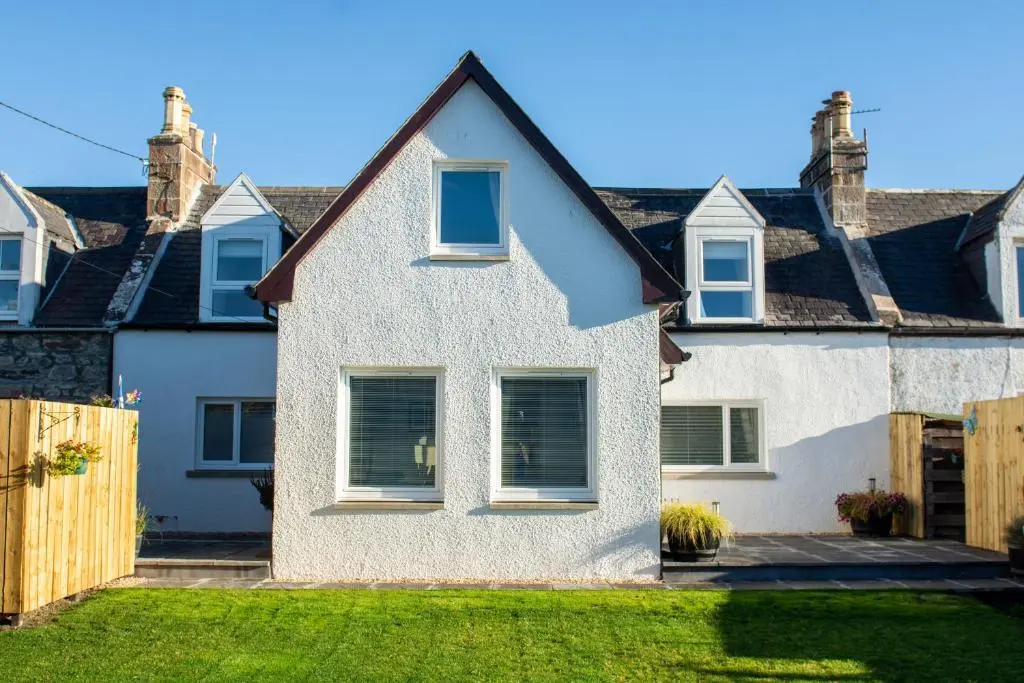 a white house with a fence in a yard at Stunning Country Cottage in Ardross Close To Traitors Castle & NC500 in Boath