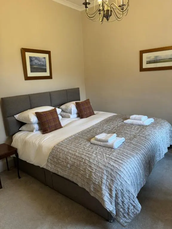 a bedroom with a large bed with towels on it at Aultnaskiach House Apartment, Inverness in Inverness