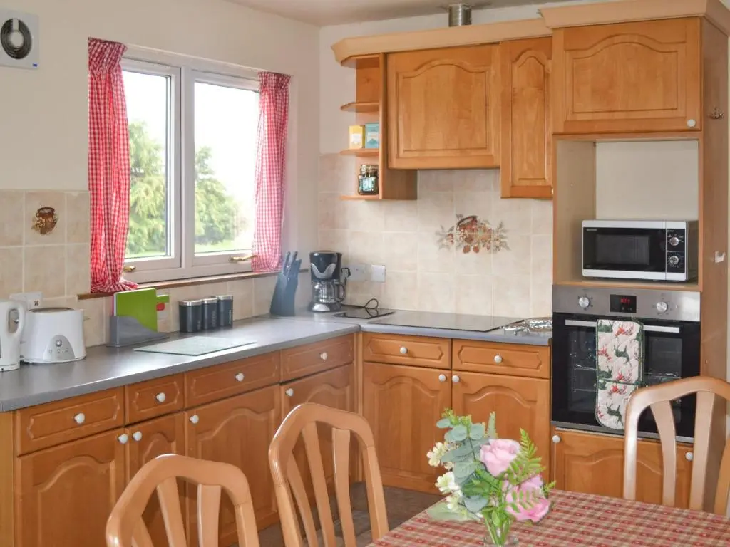 a kitchen with wooden cabinets and a table with chairs at The Junipers in Tain