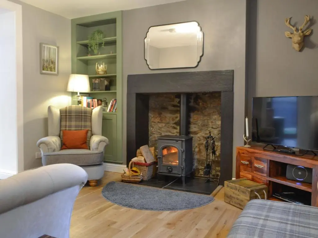 a living room with a fireplace and a tv at Logiemar Cottage in Ballater