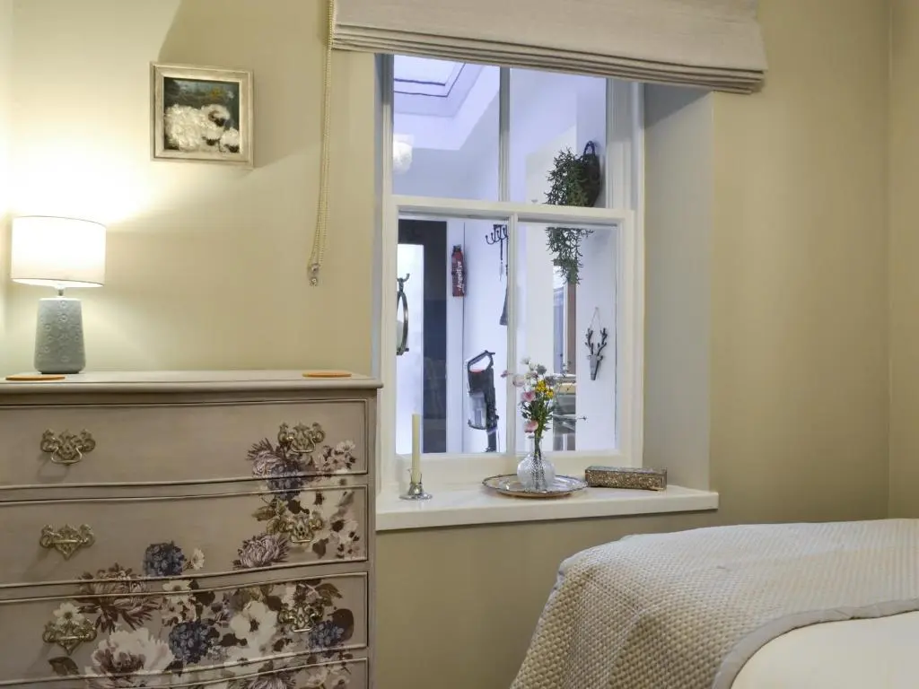 a bedroom with a dresser and a window at Logiemar Cottage in Ballater