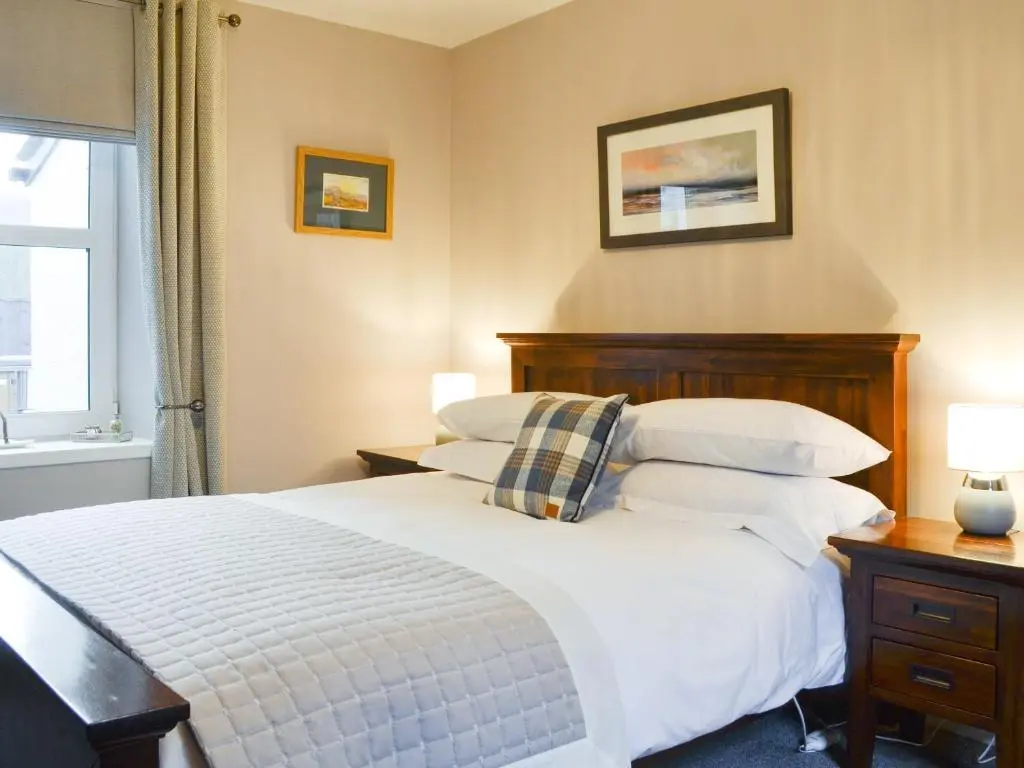 a bedroom with a bed with white sheets and pillows at Logiemar Cottage in Ballater