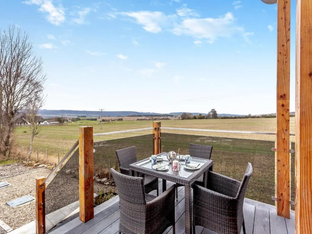 a table and chairs on a porch with a view of a field at Learag in Culbokie