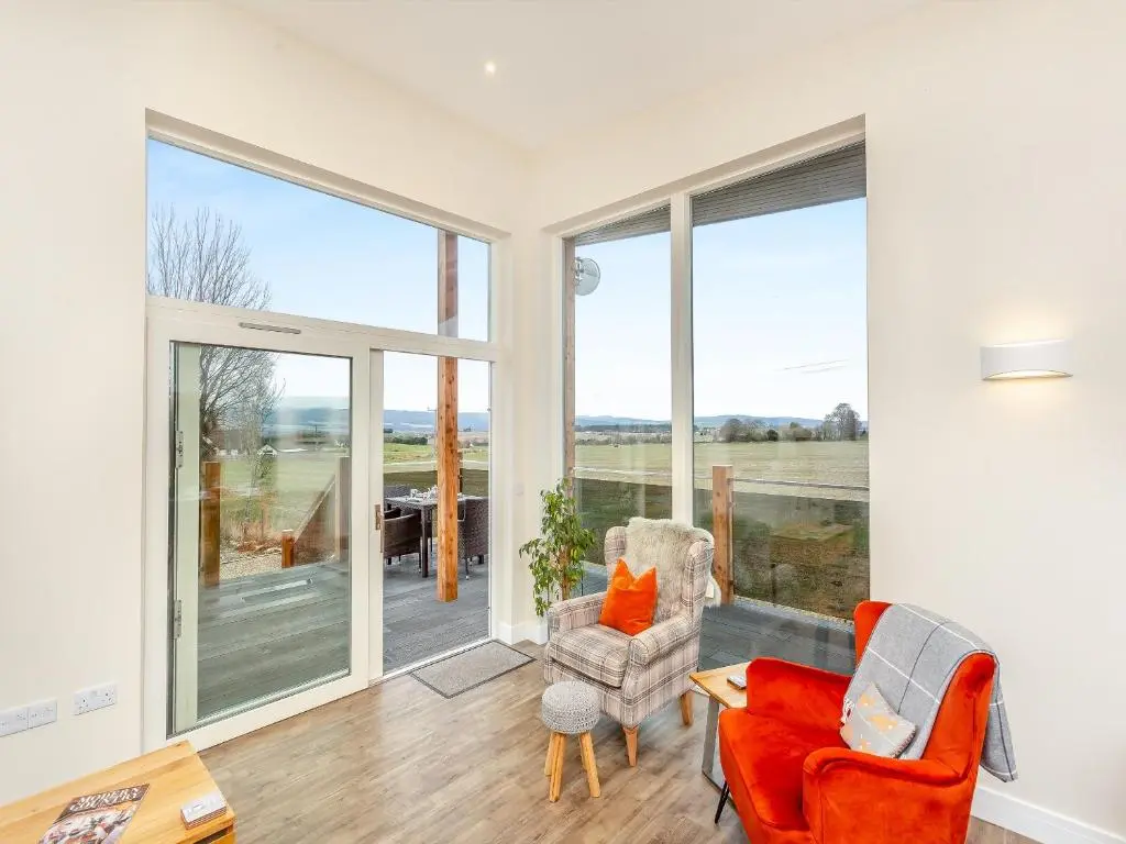 a living room with sliding glass doors and chairs at Learag in Culbokie