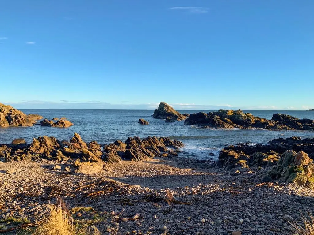 a rocky beach with rocks in the water at Seahaven Cottage in Portknockie