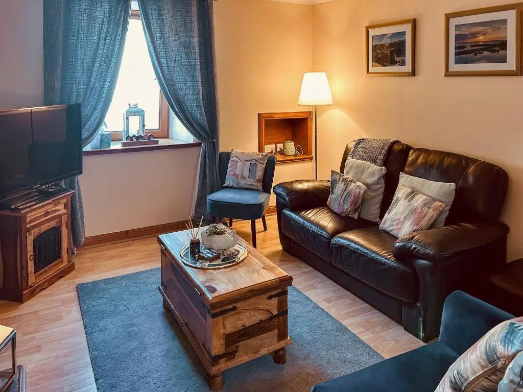 a living room with a leather couch and a tv at Seahaven Cottage in Portknockie