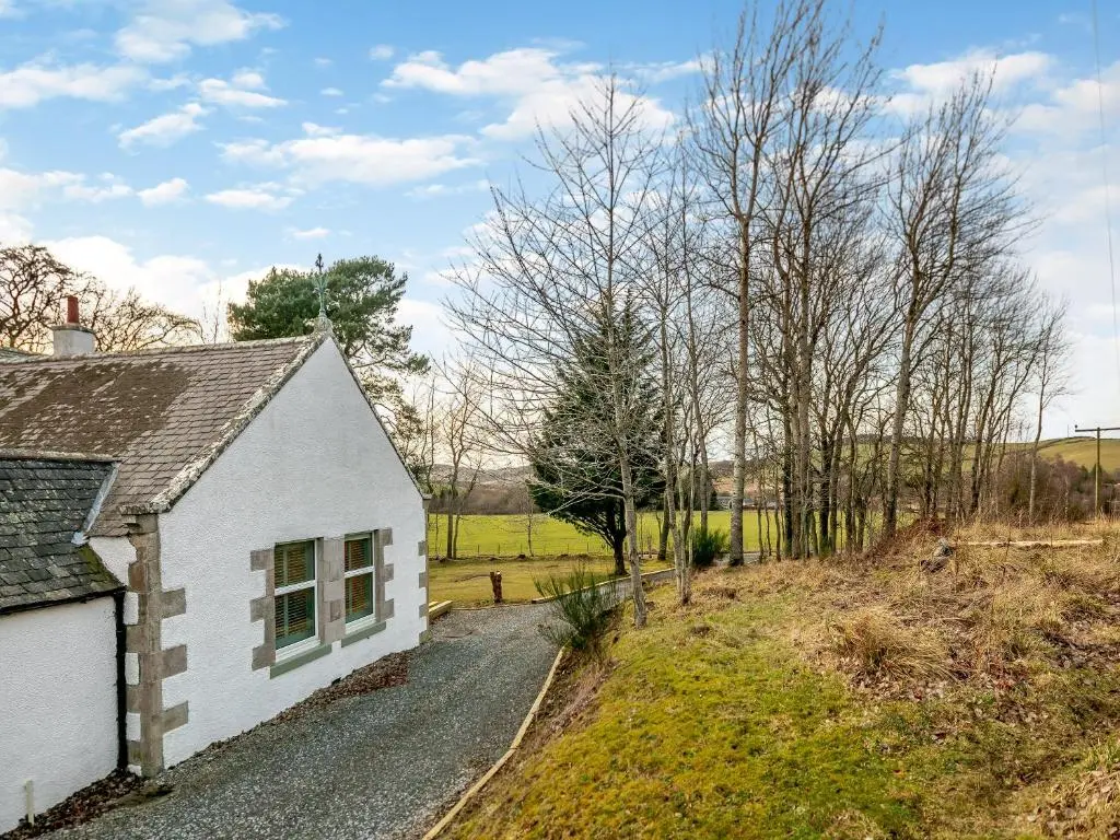 a small white house on a gravel road at Rowan Cottage in Huntly