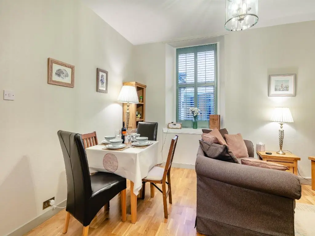 a living room with a table and a couch at Rowan Cottage in Huntly