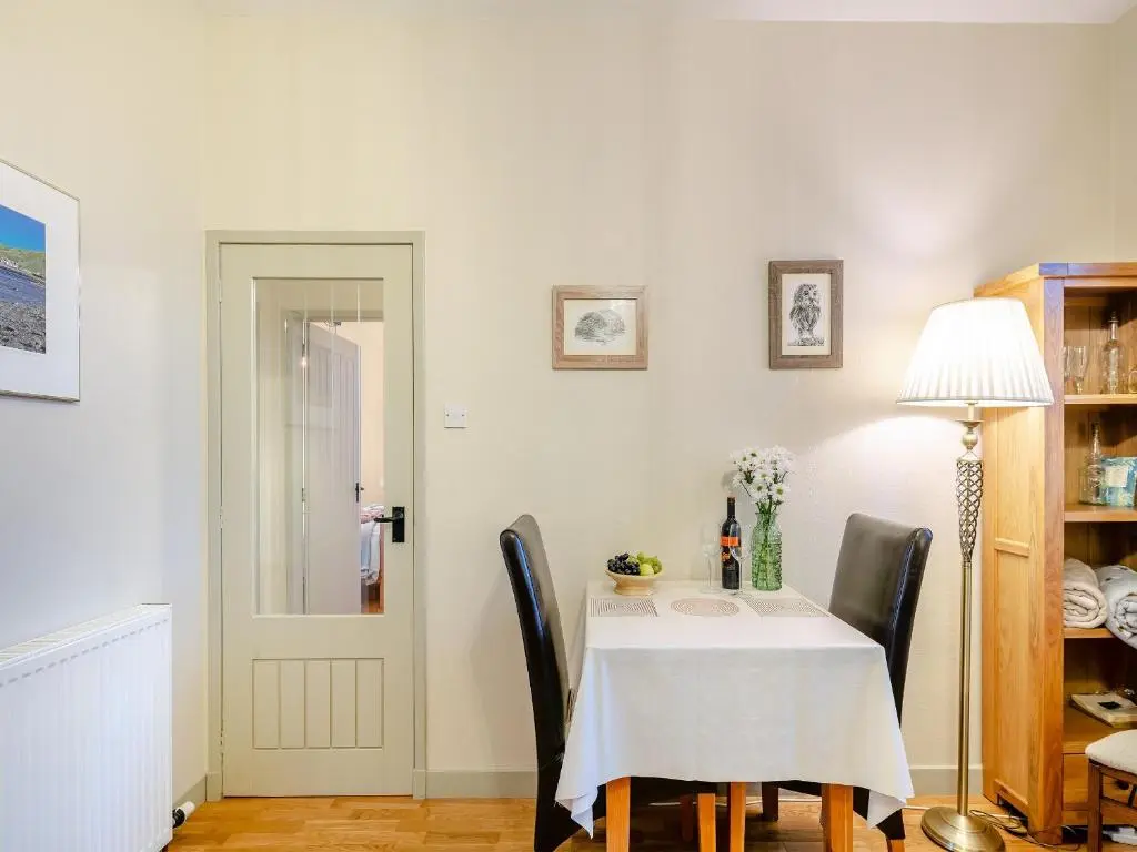 a dining room with a white table and chairs at Rowan Cottage in Huntly