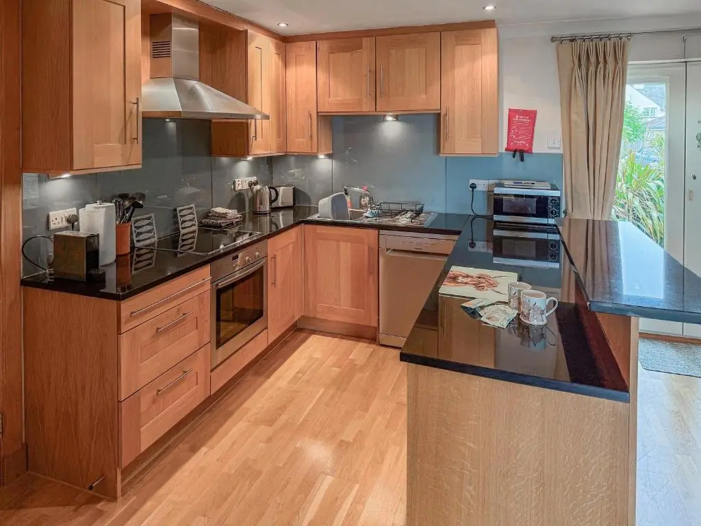 a kitchen with wooden cabinets and black counter tops at No4 The Links Apartments in Brora