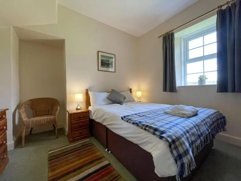 a bedroom with a bed and a window and a chair at Pine Cottage - Dalcross in Dalcross