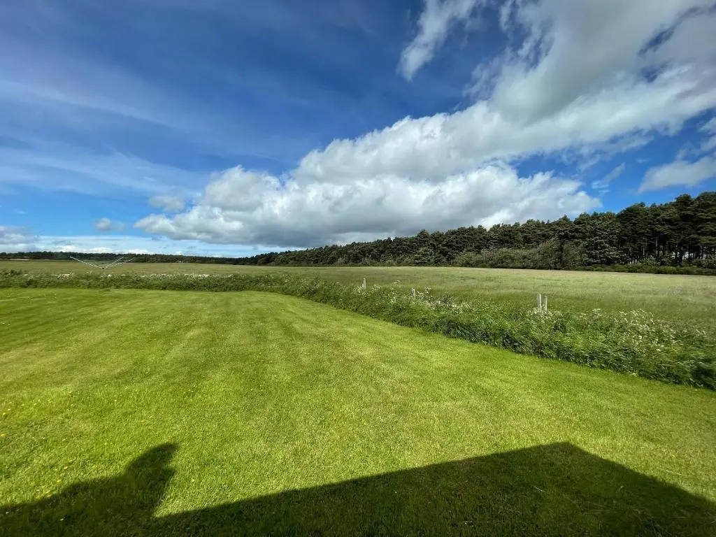 a shadow of a person taking a picture of a field at Pine Cottage - Dalcross in Dalcross