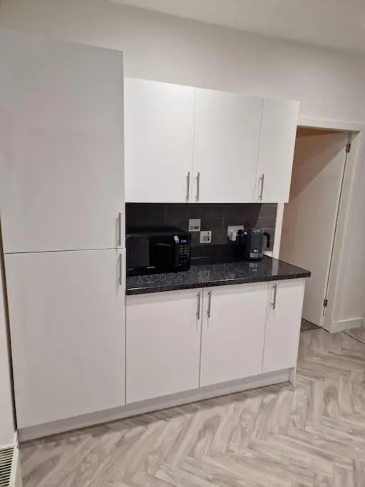 a kitchen with white cabinets and a black counter top at Catalina - Modern 2 bedroom bungalow in Elgin
