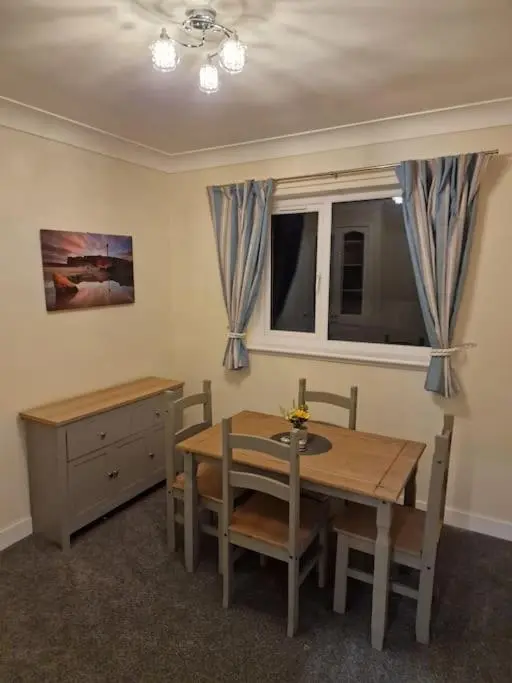 a dining room with a table and chairs and a window at Catalina - Modern 2 bedroom bungalow in Elgin