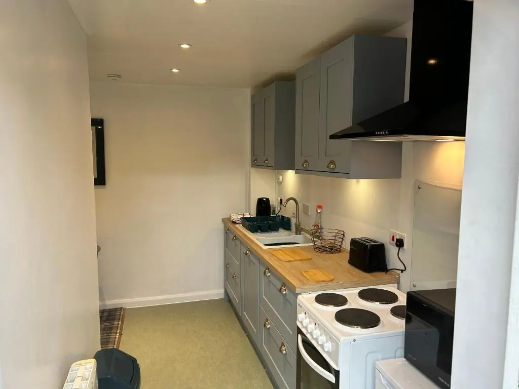 a kitchen with a stove and a counter top at One bed and bathroom with kitchen for self catering Alness in Alness