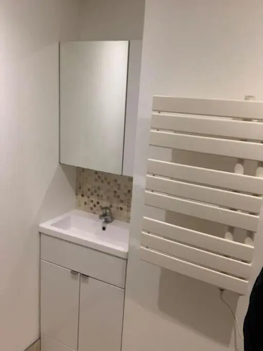 a white bathroom with a sink and a mirror at Luxury studio flat in a coastal town of Nairn in Nairn