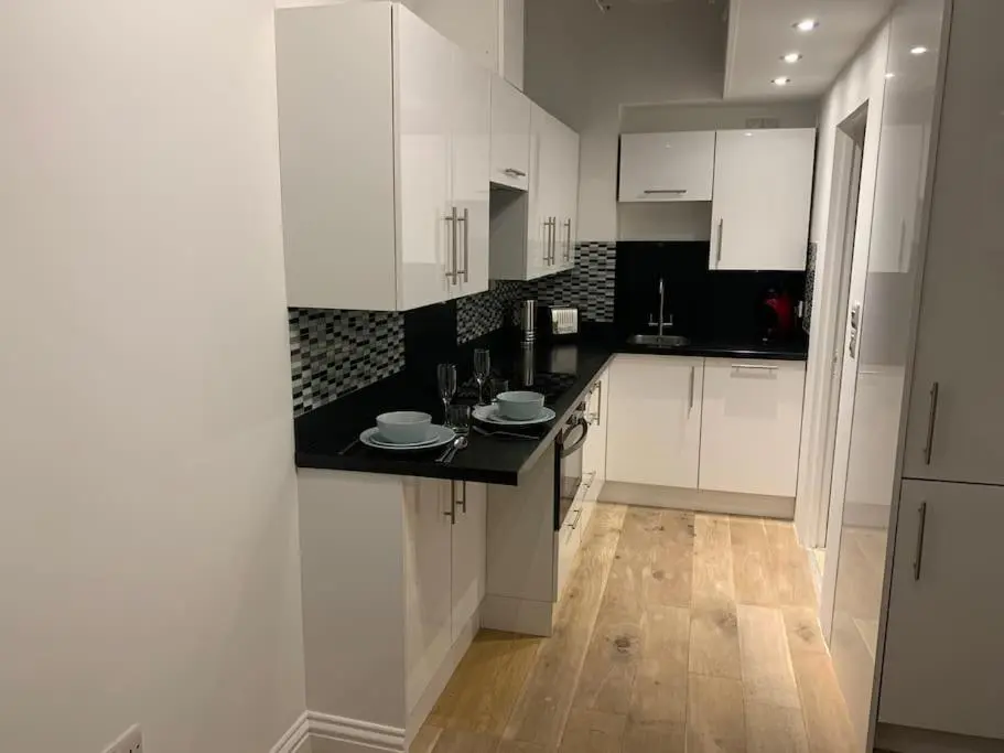 a kitchen with white cabinets and a black counter top at Luxury studio flat in a coastal town of Nairn in Nairn