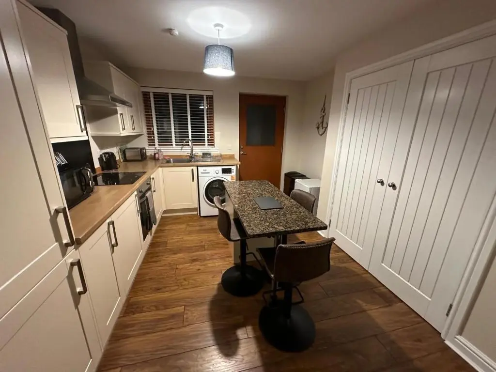 a kitchen with a table in the middle of it at Pebble Cottage in Golspie