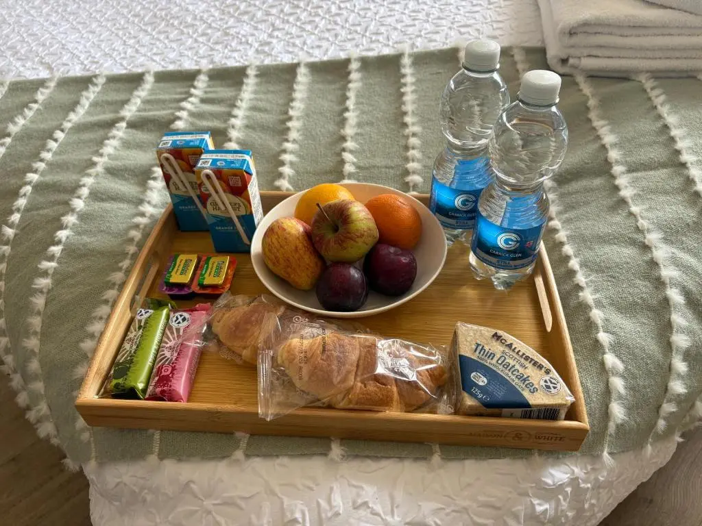 a tray with a plate of food and bottles of water at Carnegie Lodgings, Tain in Tain