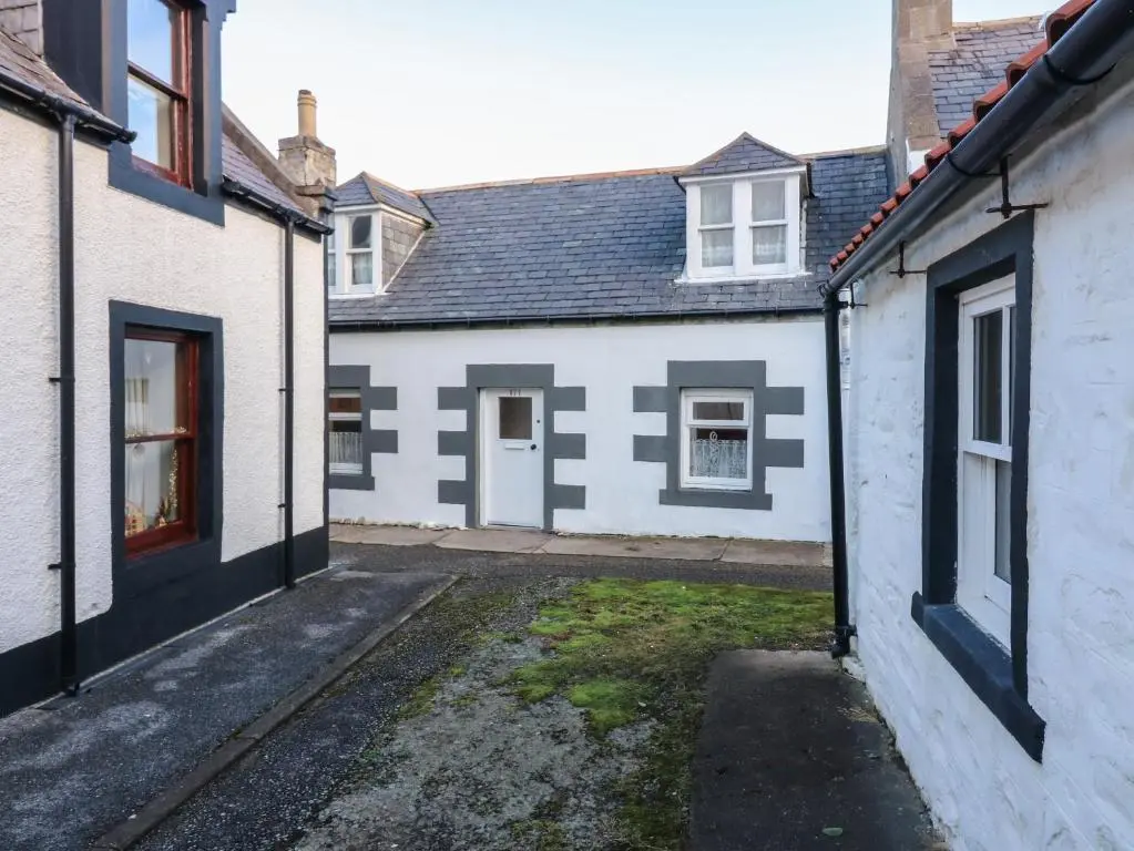 an empty courtyard of a white house with windows at 171 Seatown in Buckie