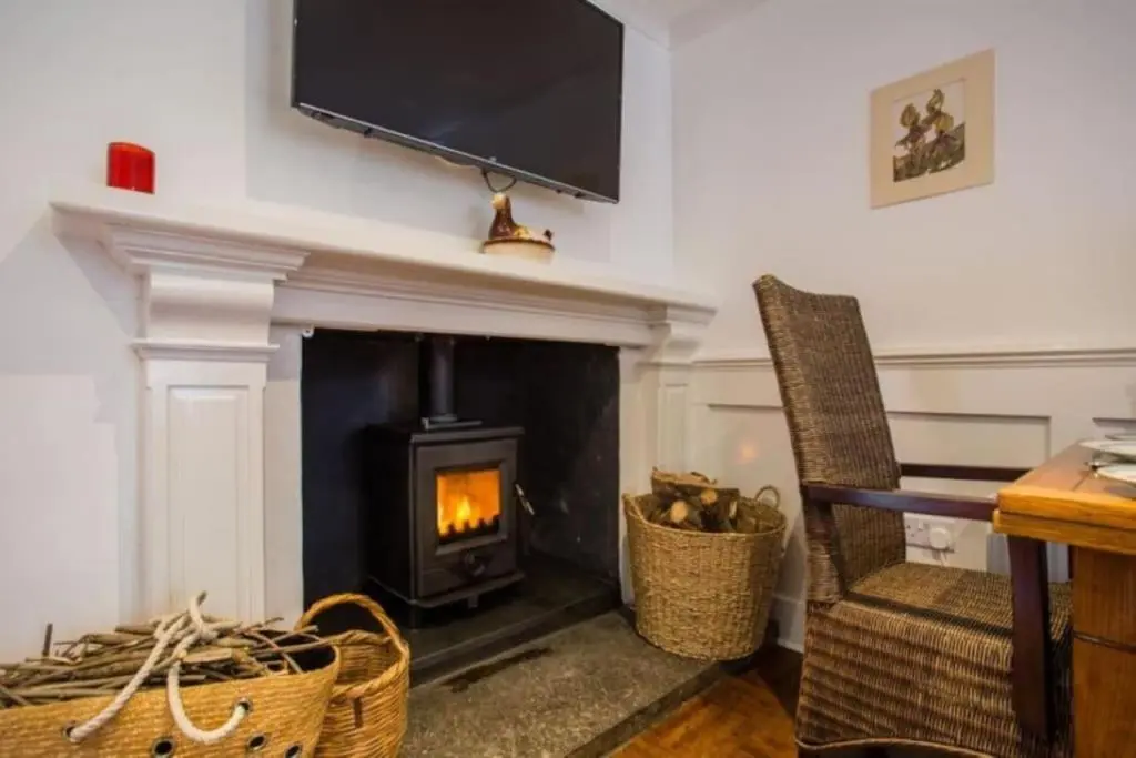 a living room with a fireplace with a tv above it at The Garden Flat - Ardullie Lodge in Dingwall