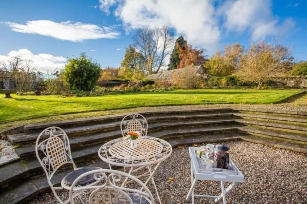 a table and chairs sitting on a patio with stairs at The Garden Flat - Ardullie Lodge in Dingwall