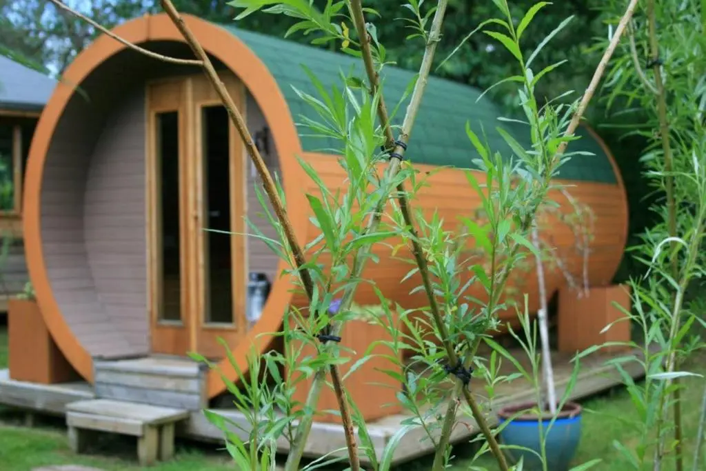 a small circular house with a door in a garden at BCC Lochness Hostel pods in Bearnock