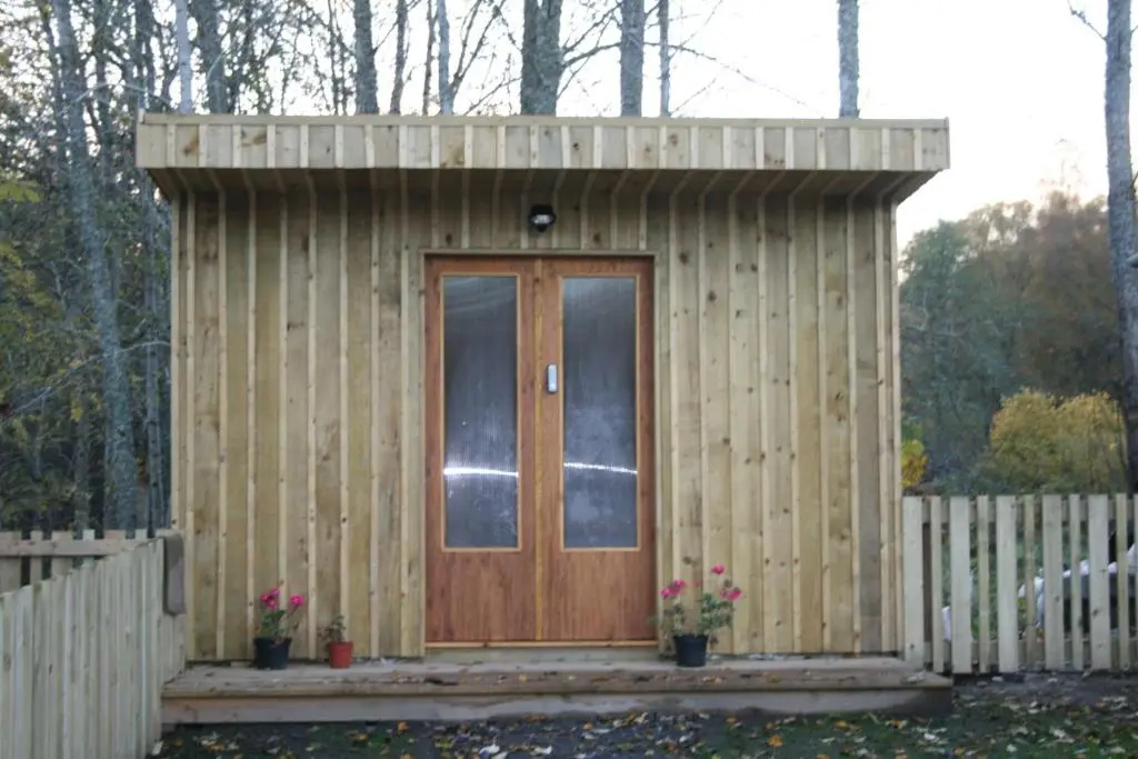 a small wooden shed with a wooden door at BCC Lochness Hostel pods in Bearnock