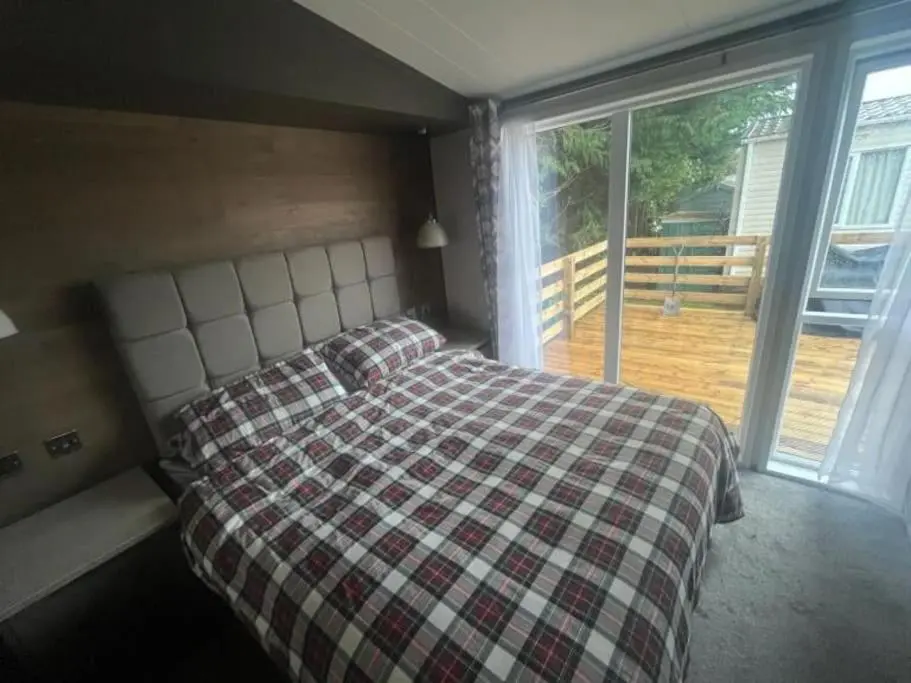 a bedroom with a bed with a checkered blanket at Corrie Fee Lodge in Boat of Garten