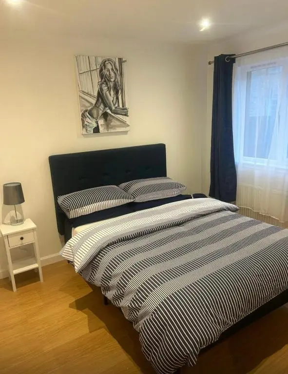 a bedroom with a striped bed with a window at Balmanach Court in Beauly