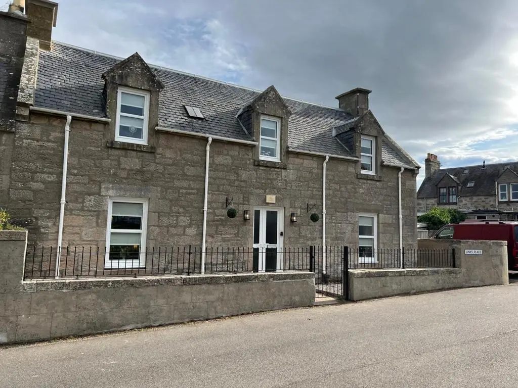 a brick house with a fence in front of it at 1 Links Place in Nairn