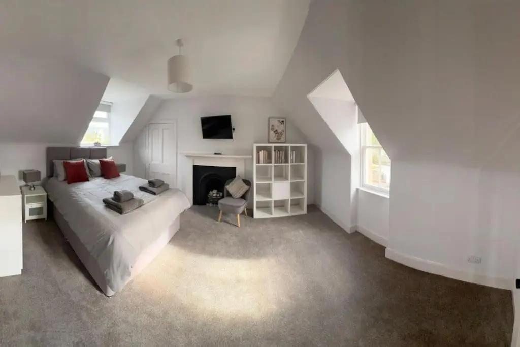 a white bedroom with a bed and a fireplace at 1 Links Place in Nairn