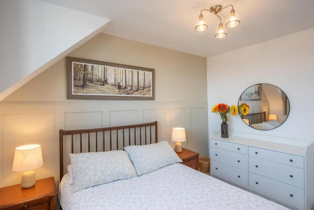 a bedroom with a bed and a mirror and a dresser at Mabels Cottage by the beach in Nairn