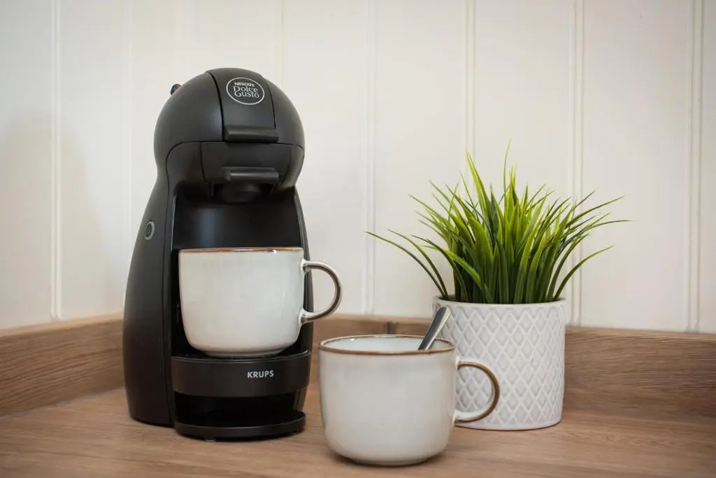 a coffee maker sitting next to two cups of coffee at Mabels Cottage by the beach in Nairn